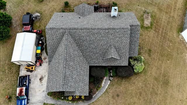 Overhead view of a house with brown shingle roof on green grass.