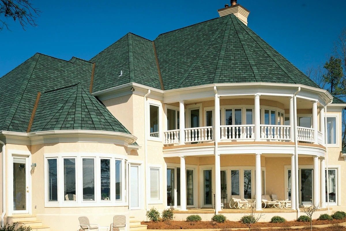 Aerial view of suburban houses with manicured lawns and cars parked in driveways on a sunny day.