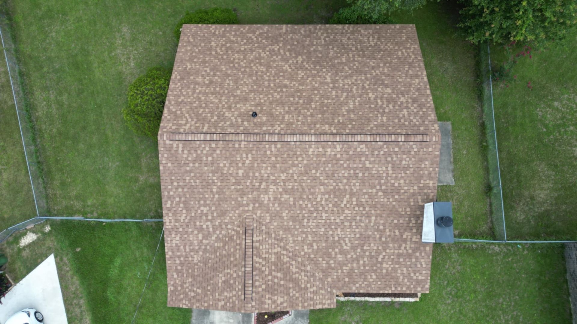 Overhead view of a house with a brown shingled roof.