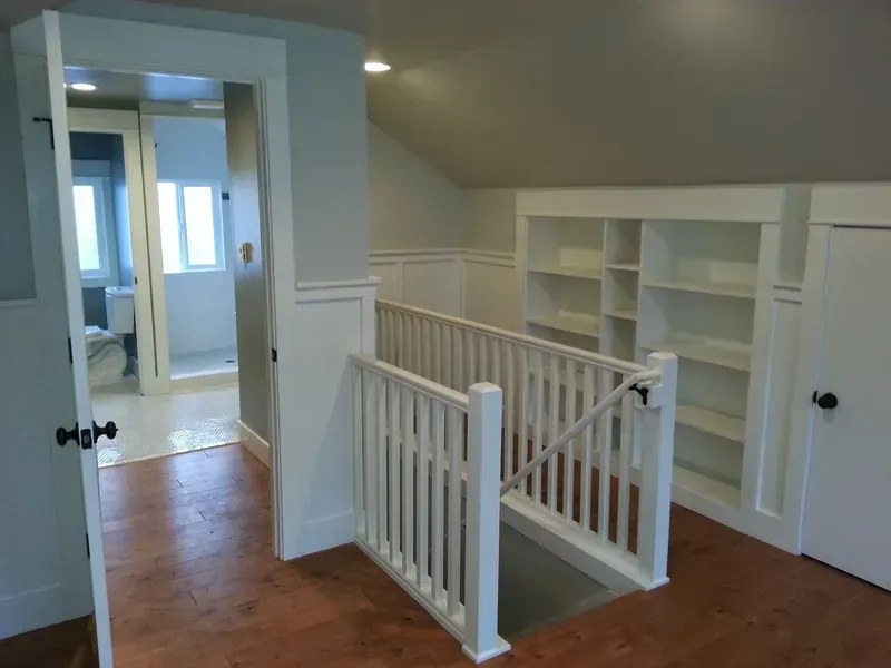 Upstairs hallway with white railings, built-in shelves, and wood flooring