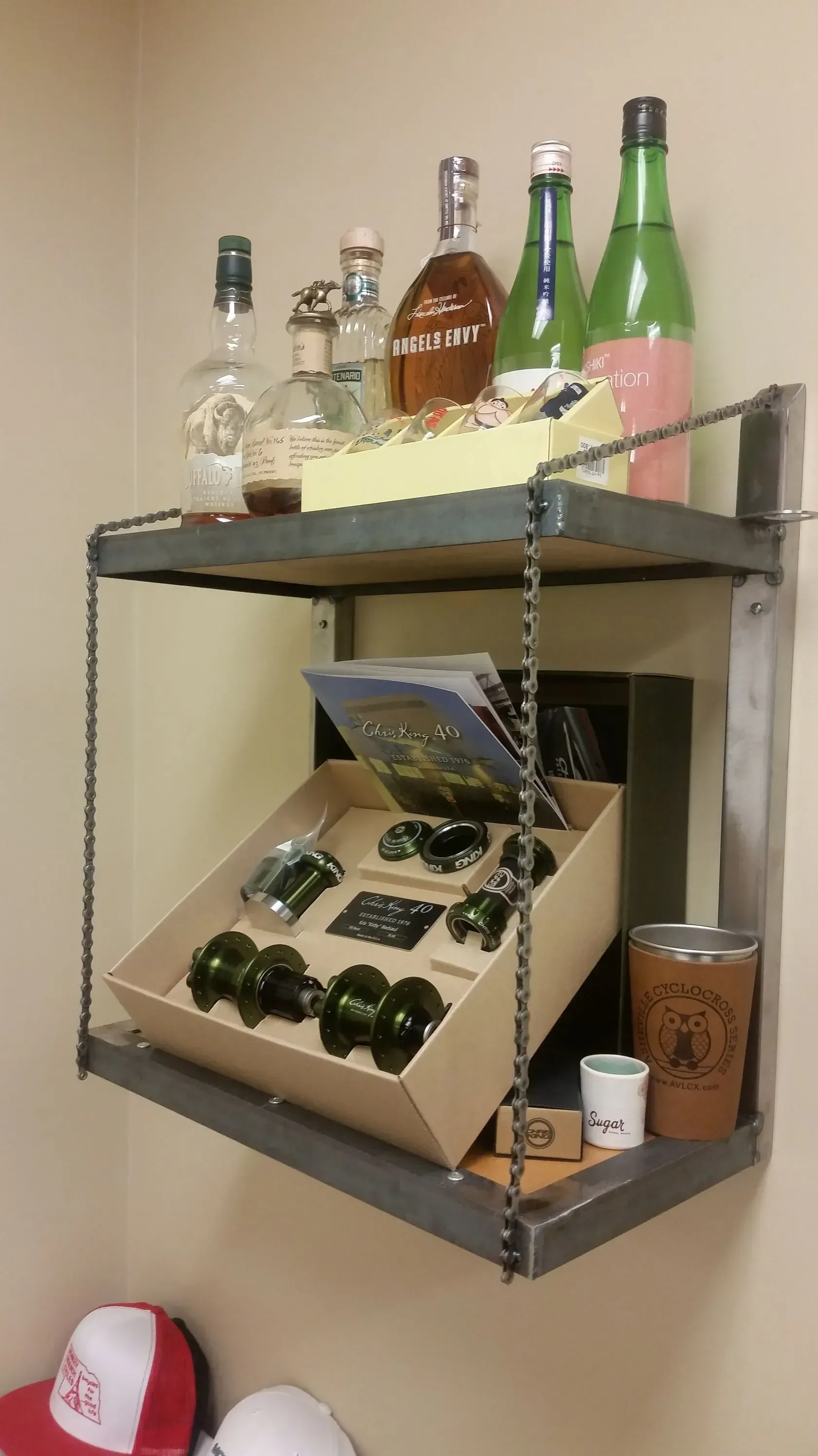 Shelf displaying liquor bottles and merchandise. The shelf is metal and supported by chains.