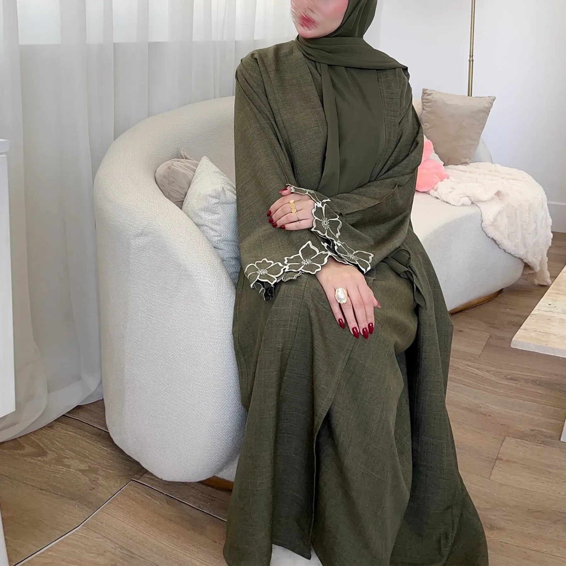 A woman in a green dress is sitting in a chair.