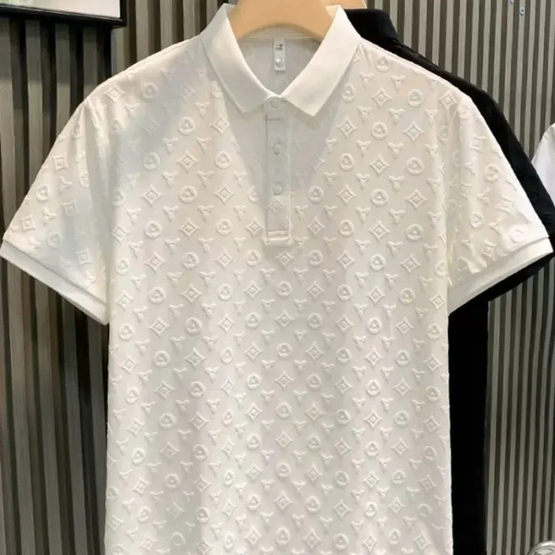 A white polo shirt with a monogram on it is hanging on a hanger.