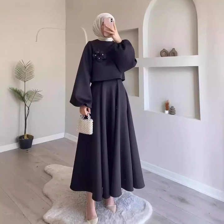 A woman wearing a hijab and a black dress is taking a picture of herself.