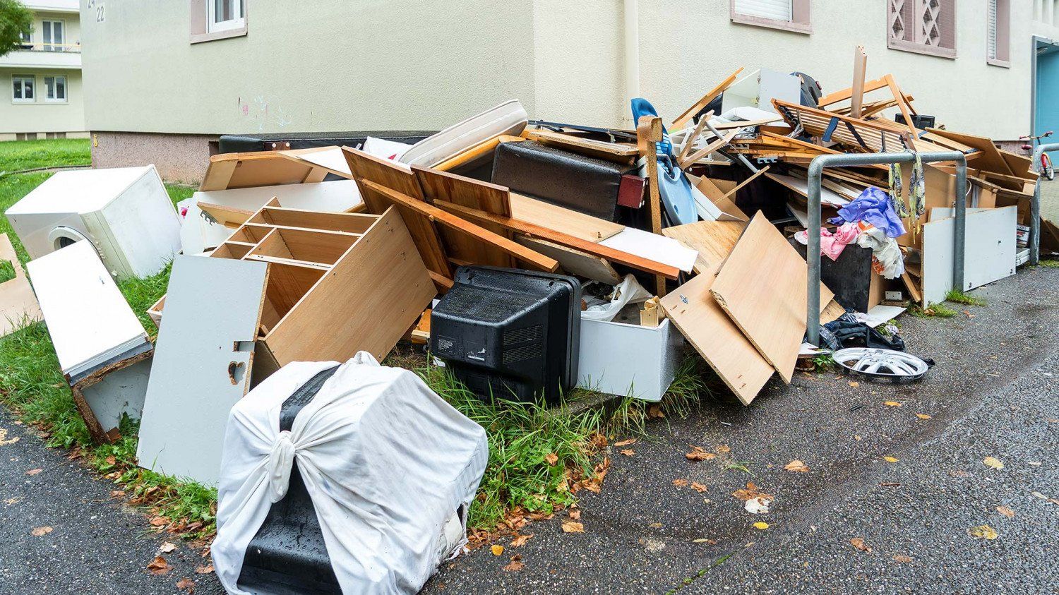 A pile of trash is sitting on the side of the road in front of a building.