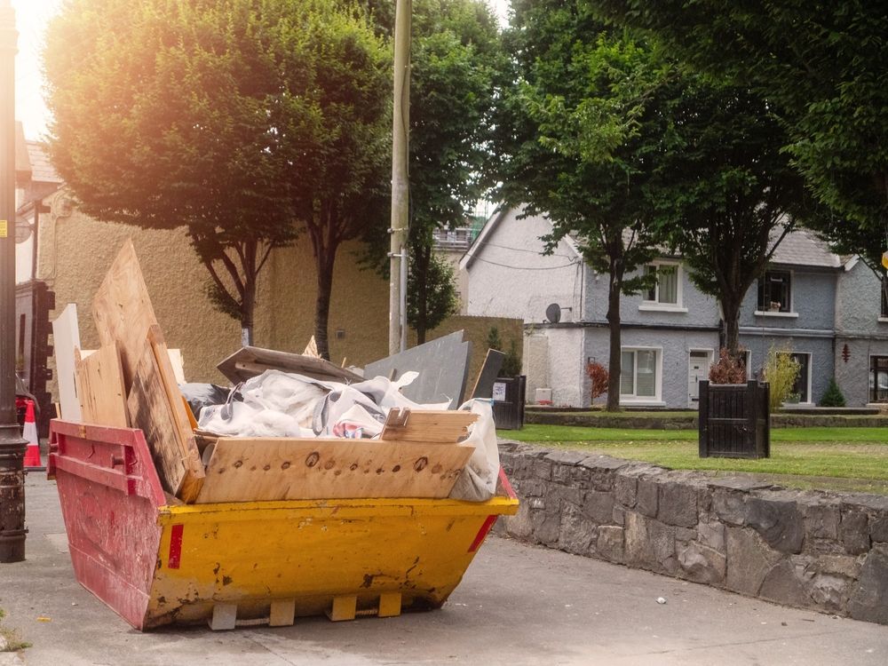 A garbage man is loading a blue trash can into a garbage truck.