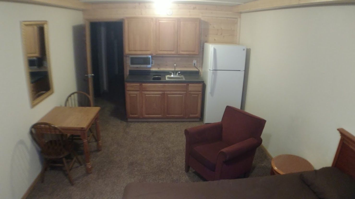White bathroom vanity with black countertop, illuminated mirror, and decorative vases.