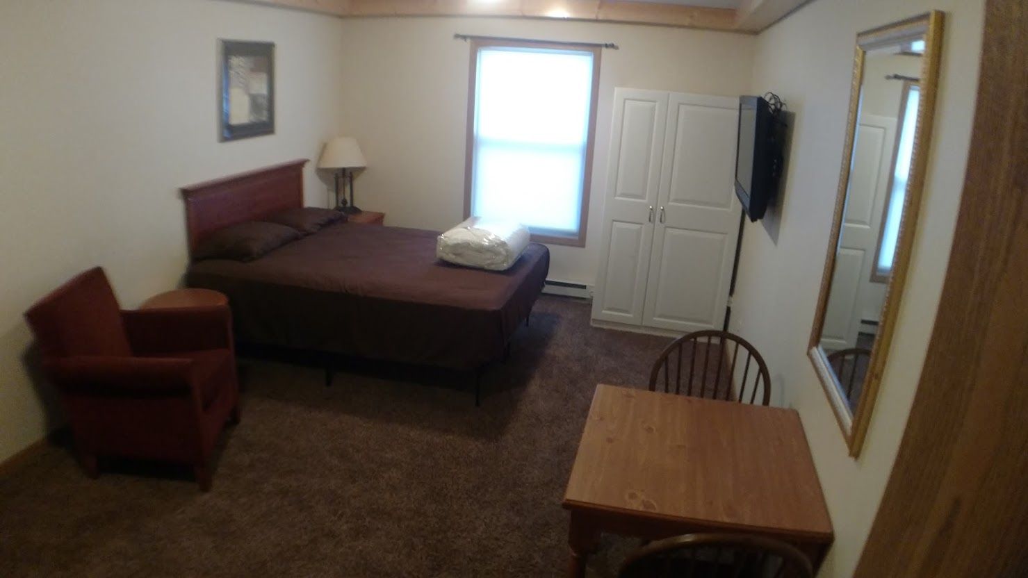 Bedroom with a bed, mirror, and a small table. Black and white bedding on a metal frame.
