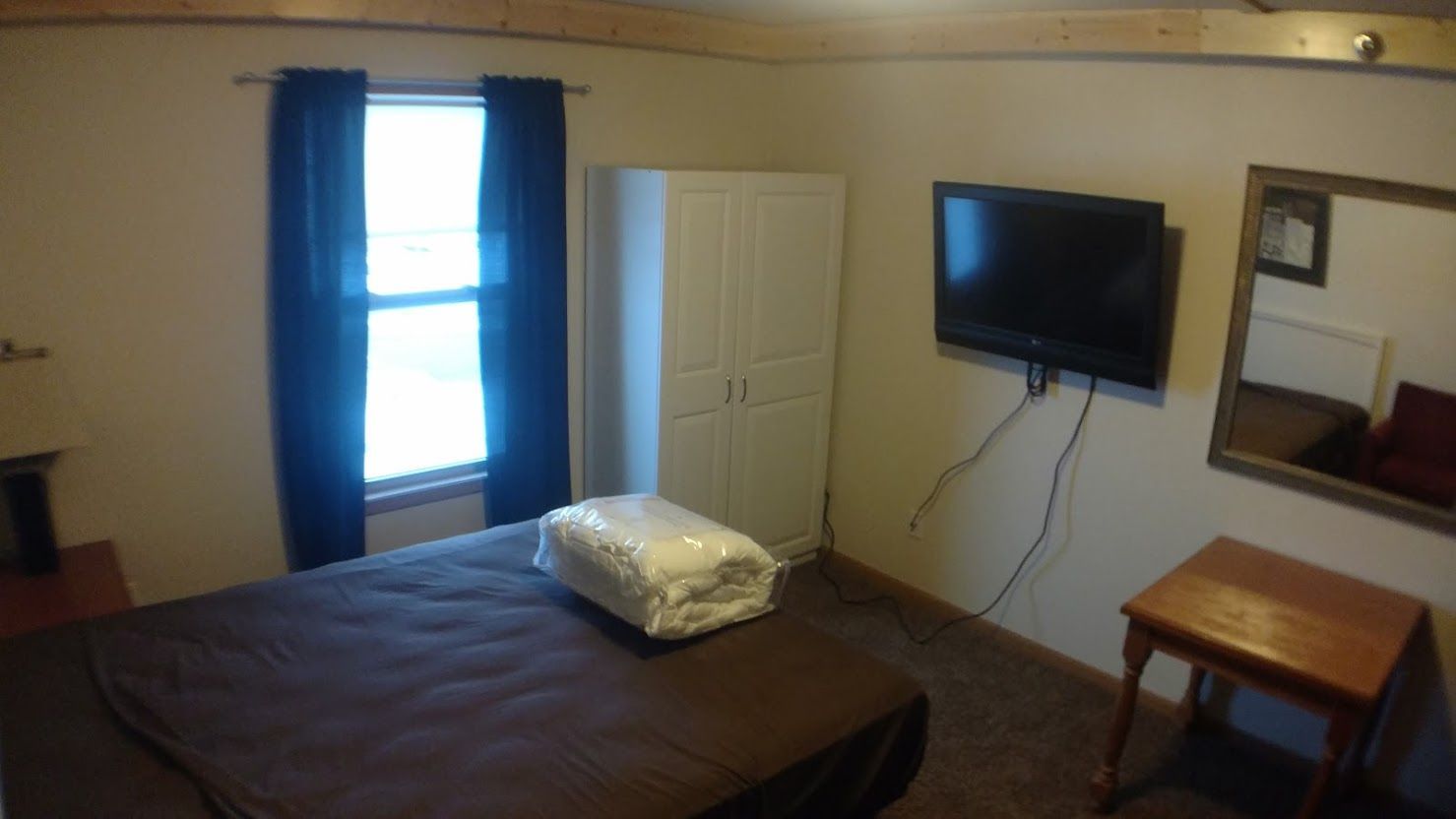 Living room with beige couch, two armchairs, a coffee table, and a window with curtains.