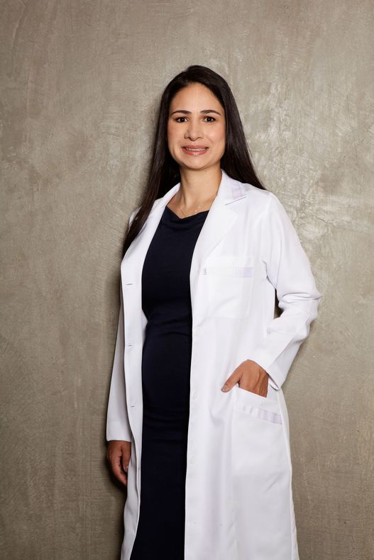 A woman is wearing a white lab coat and a black dress.