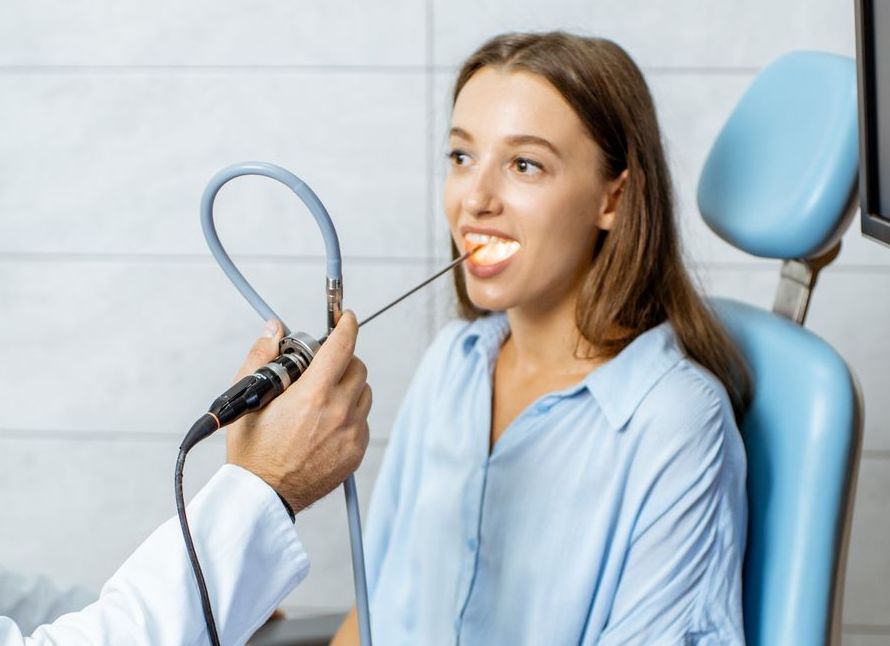 A woman is having her throat examined by a doctor.