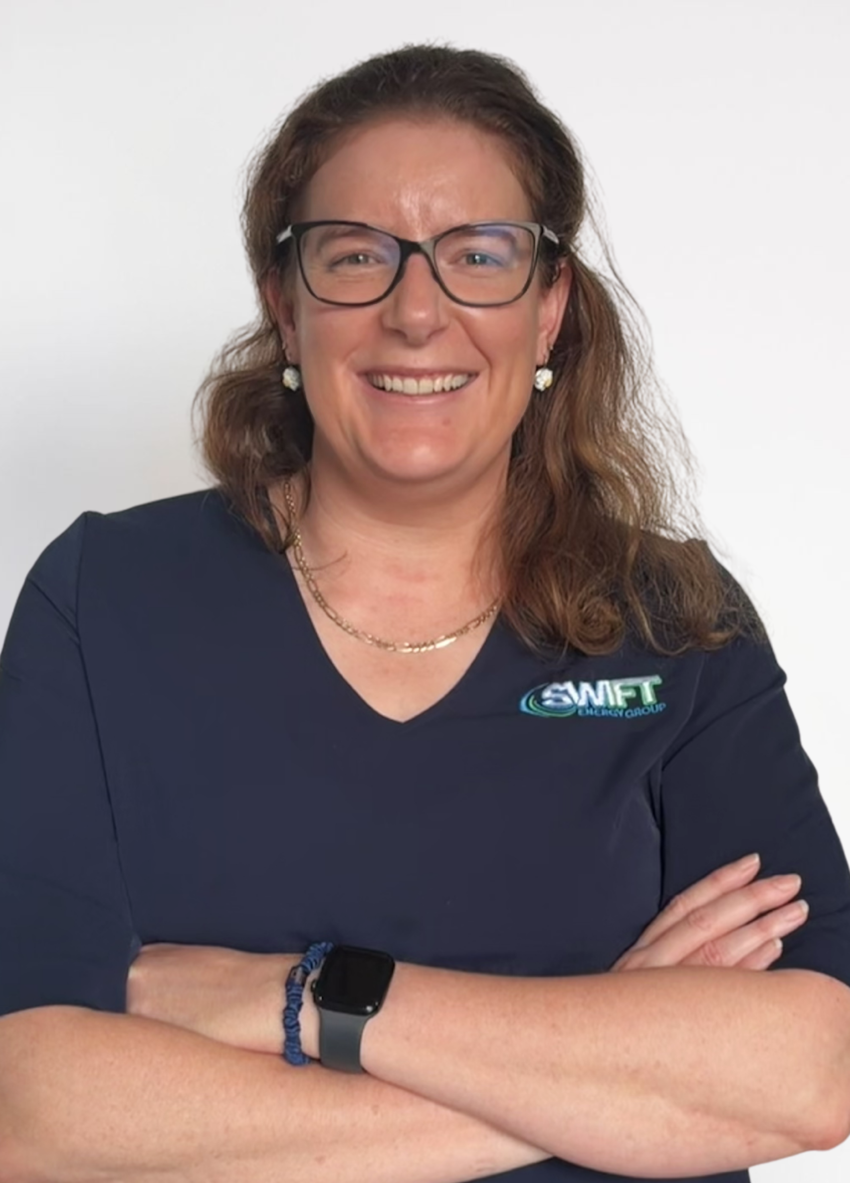Smiling person in glasses and navy shirt with arms crossed against a light background