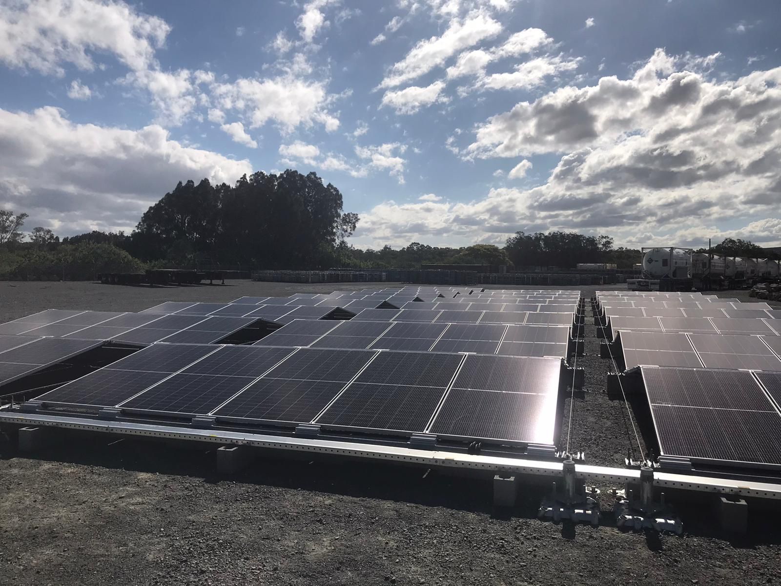 Solar panels in a field, under a partly cloudy sky.