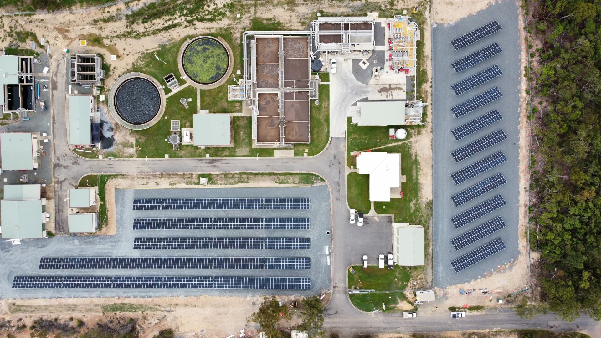 Aerial view of a wastewater treatment plant with tanks, buildings, and solar panels.