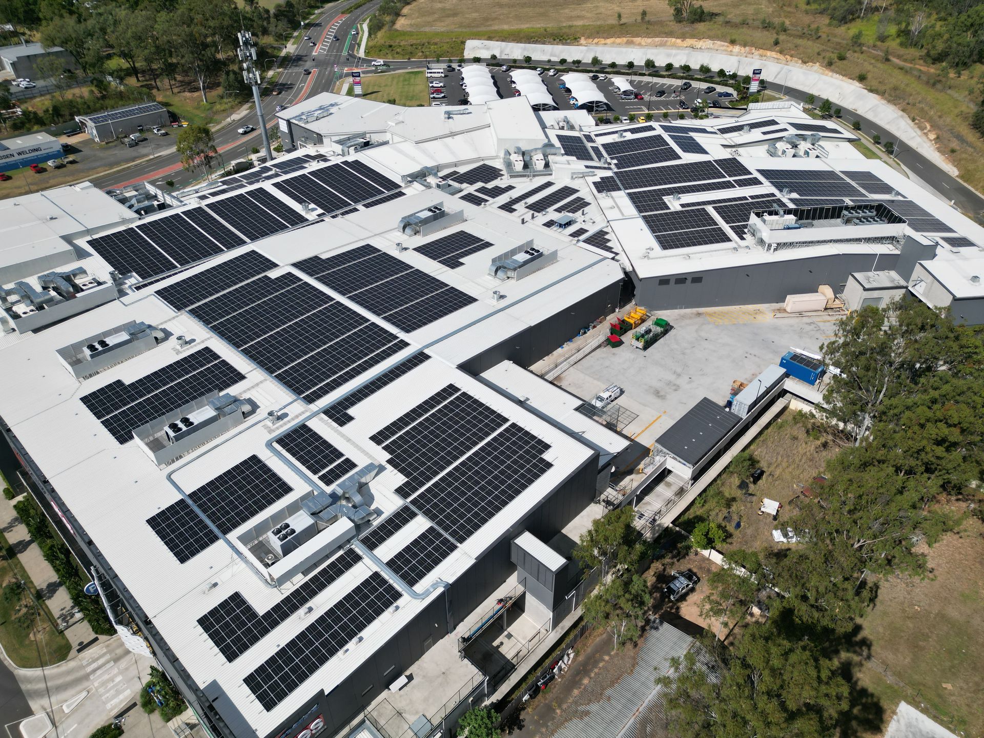 Aerial view of a commercial building with extensive solar panel array on the roof.