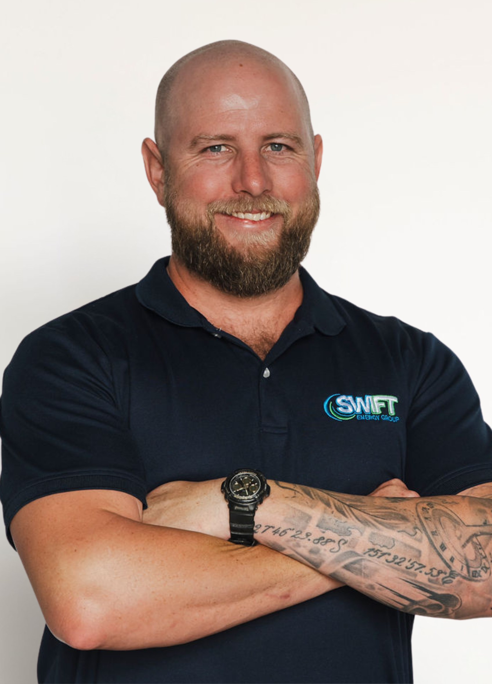 Bald man with beard wearing dark blue polo shirt, arms crossed, smiling.