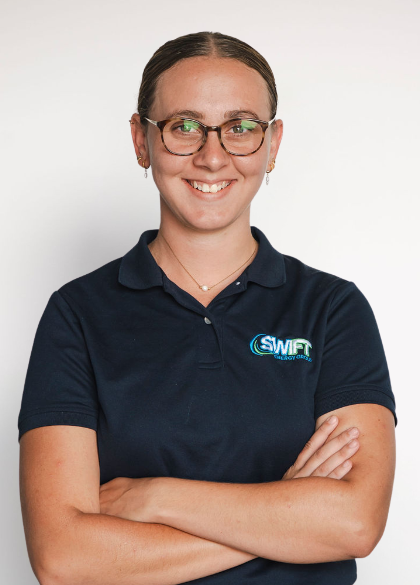 Portrait of a smiling person in glasses and a navy polo shirt with arms crossed on a white background