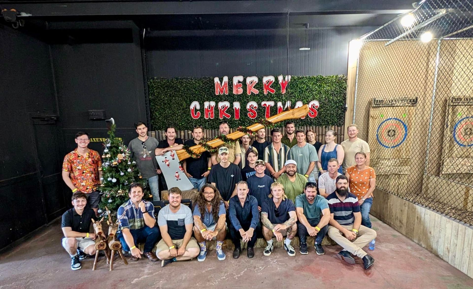 Group of people at an axe-throwing venue, celebrating Christmas. 