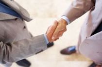 Two men in suits shaking hands, symbolizing agreement or collaboration.