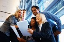 Group of diverse colleagues reviewing documents together in an office, smiling.