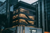 Office building at dusk with lit windows, city setting.