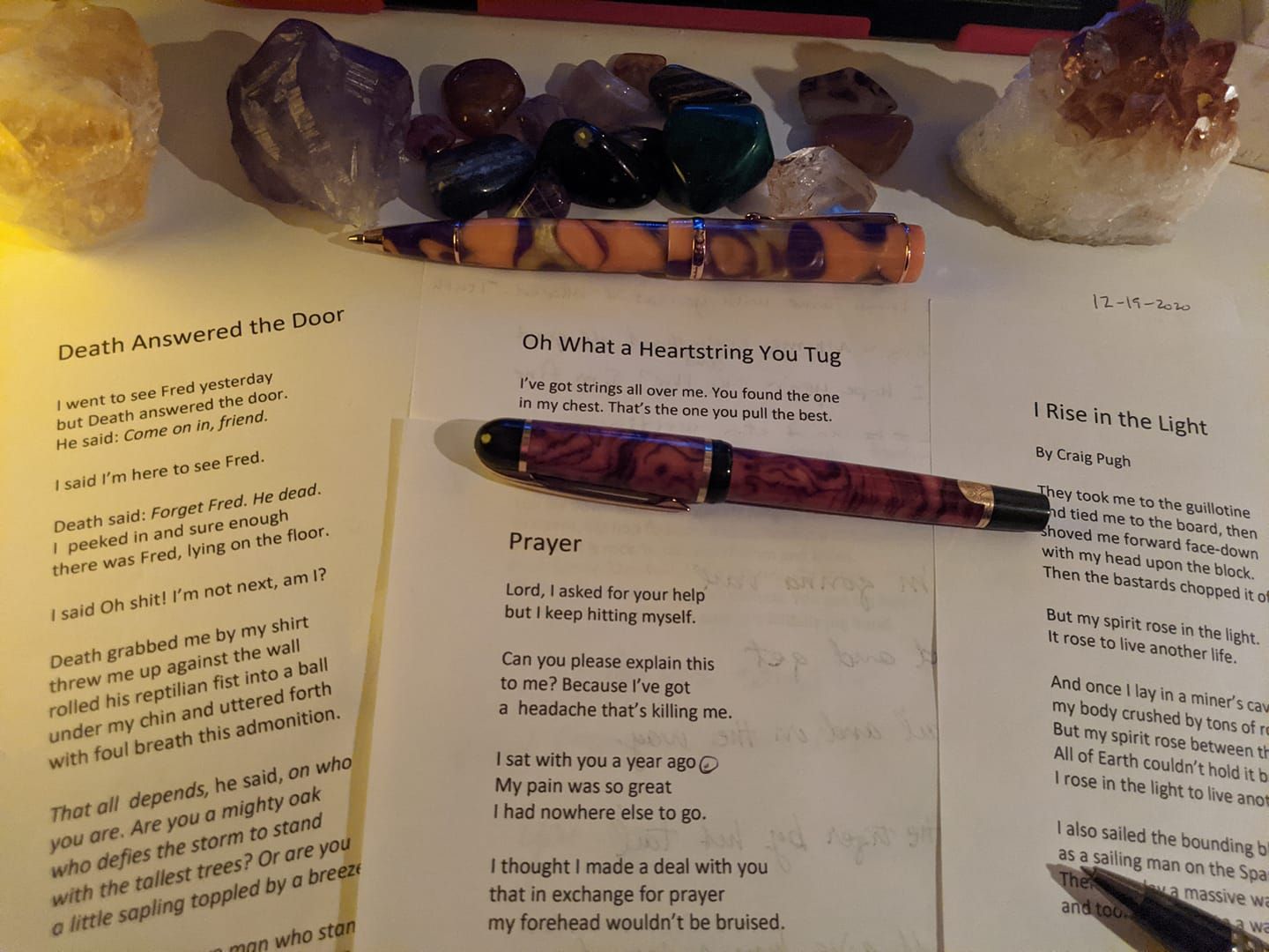 Printed spiritual pages with crystals and polished stones arranged on top and between the pages.