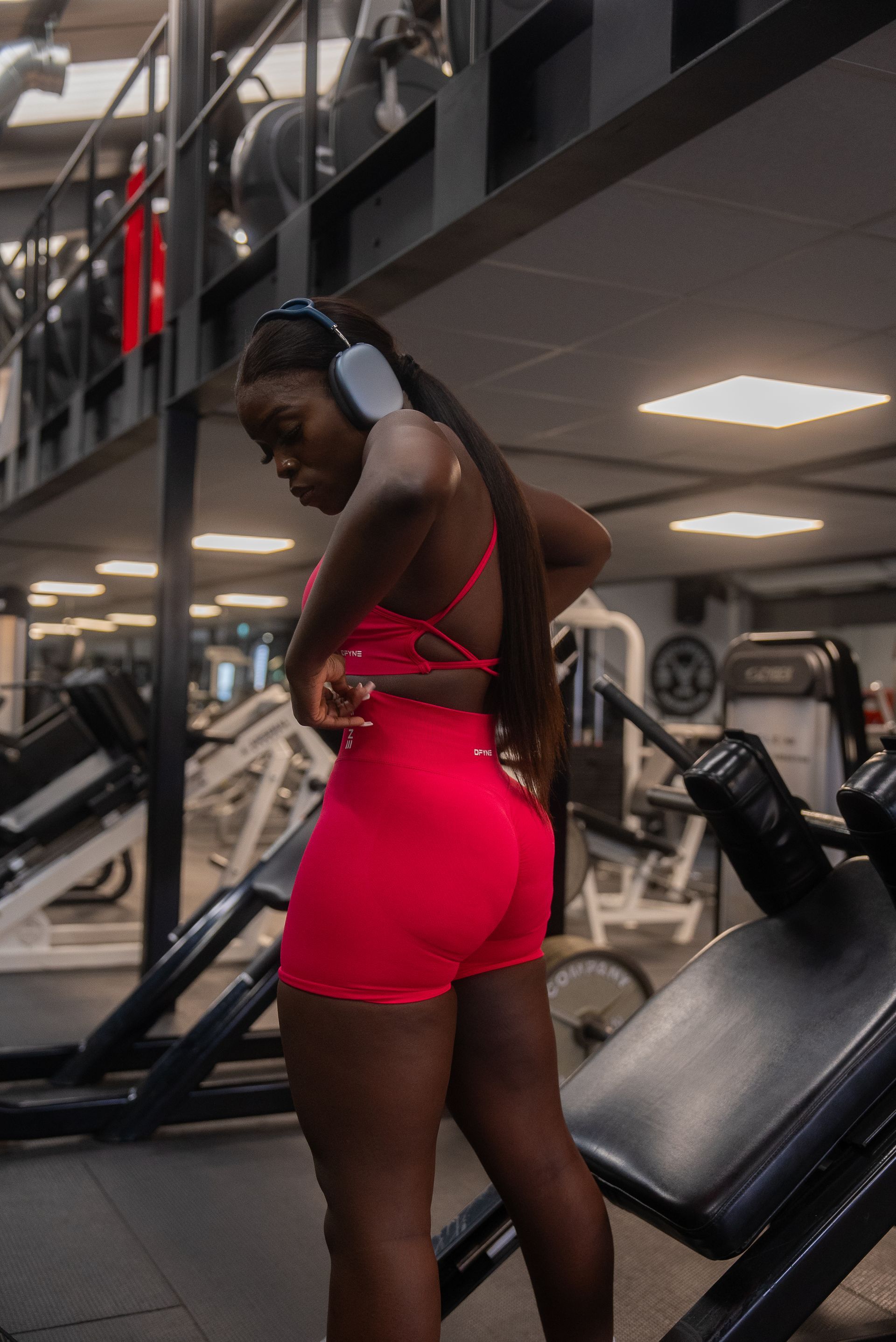 A woman wearing headphones is standing in a gym.