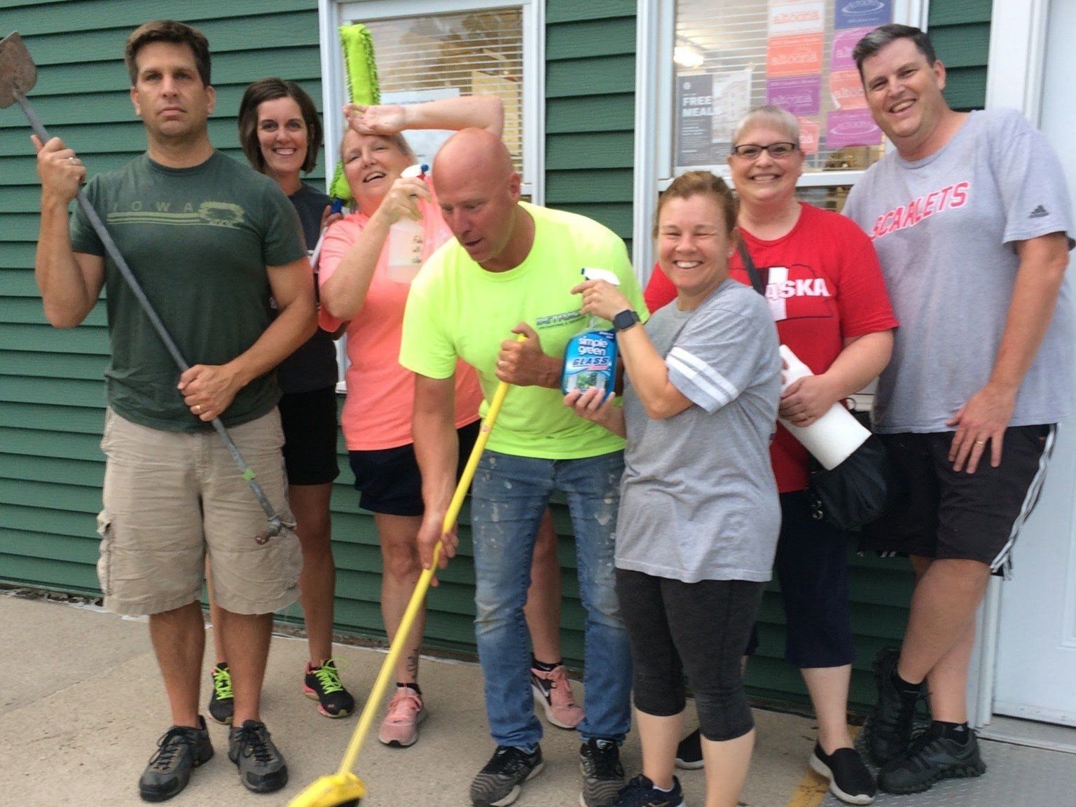 A group of people standing in front of a green building