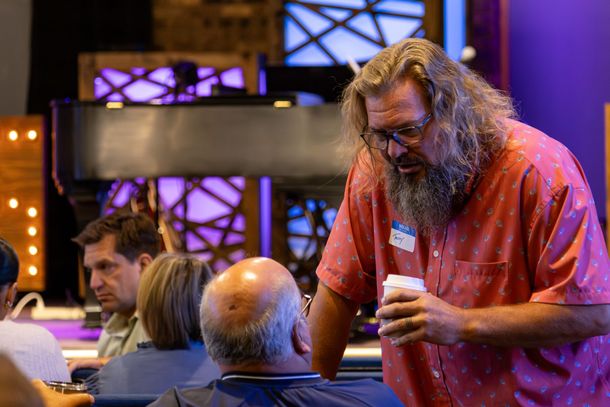 Two men are talking in front of a stained glass window