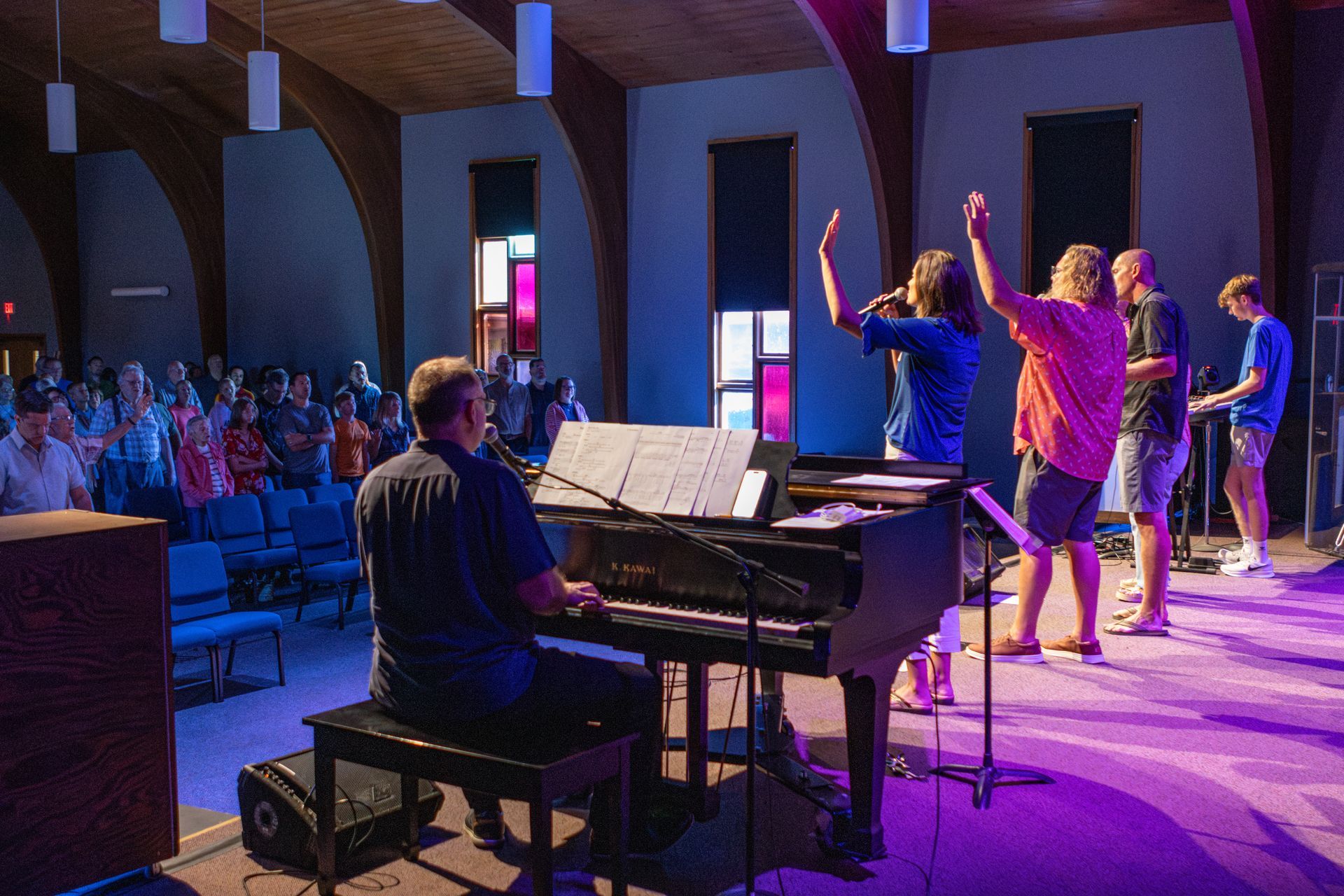 A group of people are singing and playing keyboards in a church.