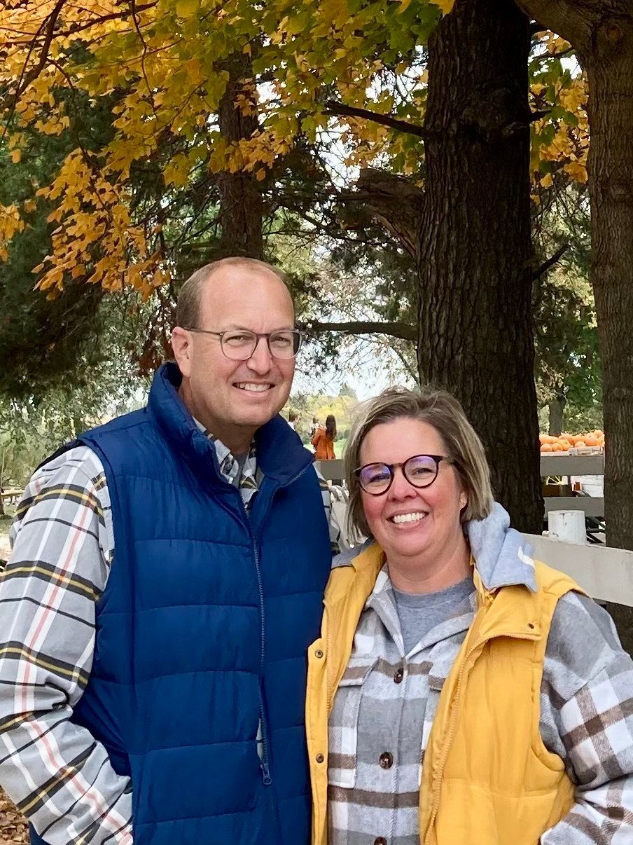 A man and a woman are posing for a picture in front of a tree.