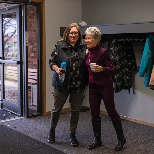 Two women standing next to each other in a hallway