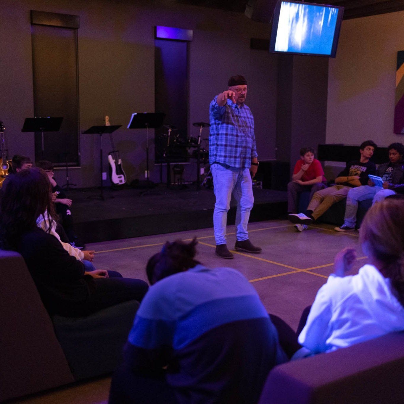 A man in a plaid shirt is standing in front of a group of people