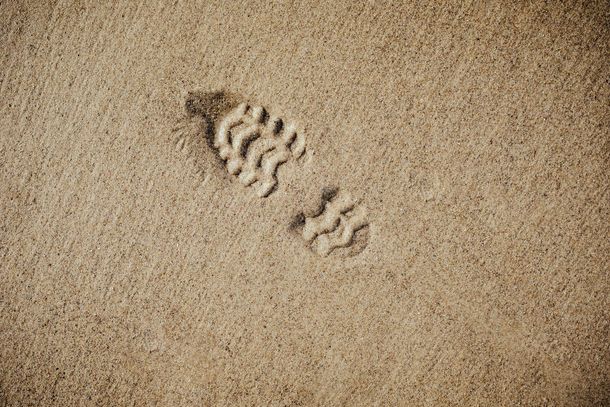 A close up of a footprint in the sand on a beach.
