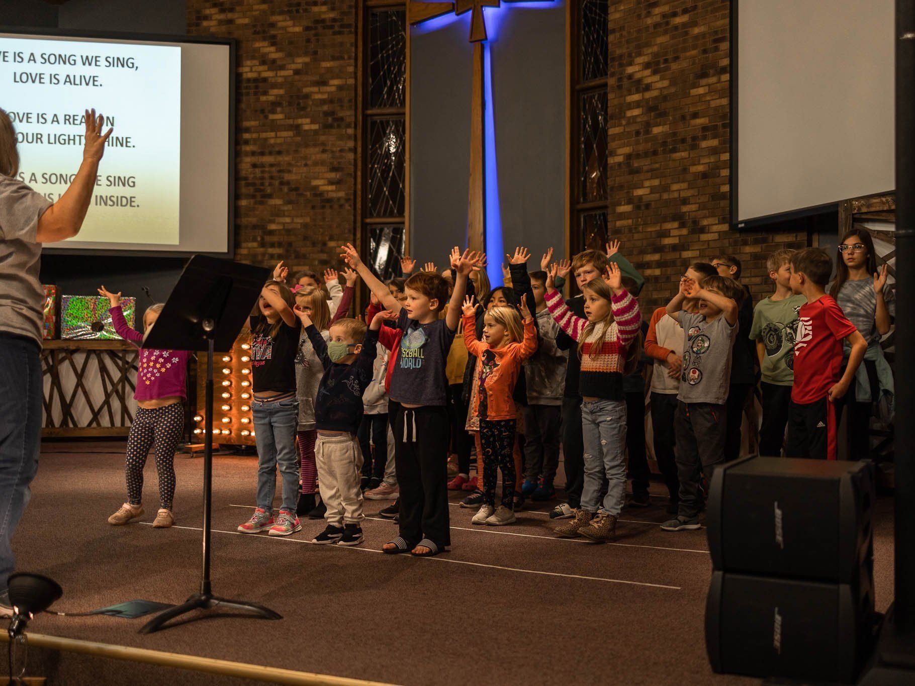 A group of children are standing on a stage with their hands in the air.