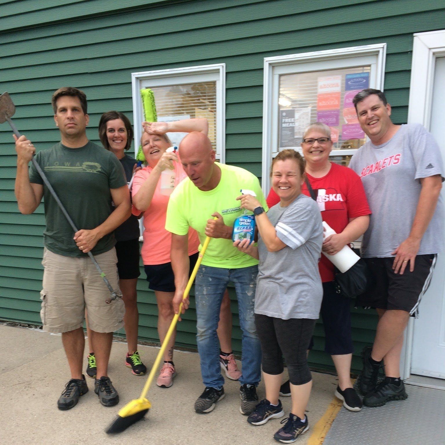 A group of people standing in front of house with cleaning supplies