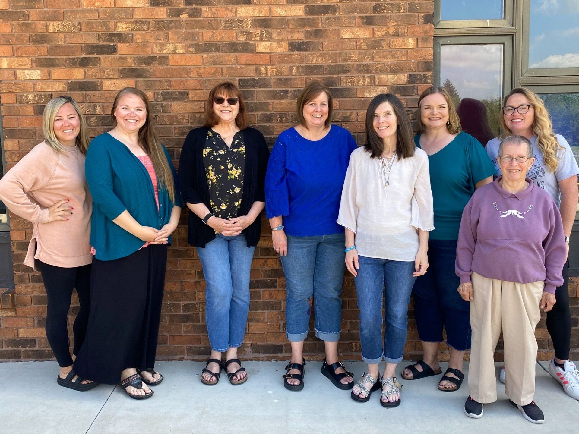 A group of women are posing for a picture in front of a brick building.