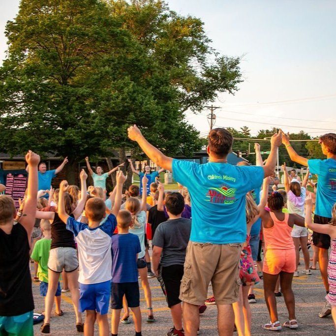 A group of children are standing in a line with their arms in the air.