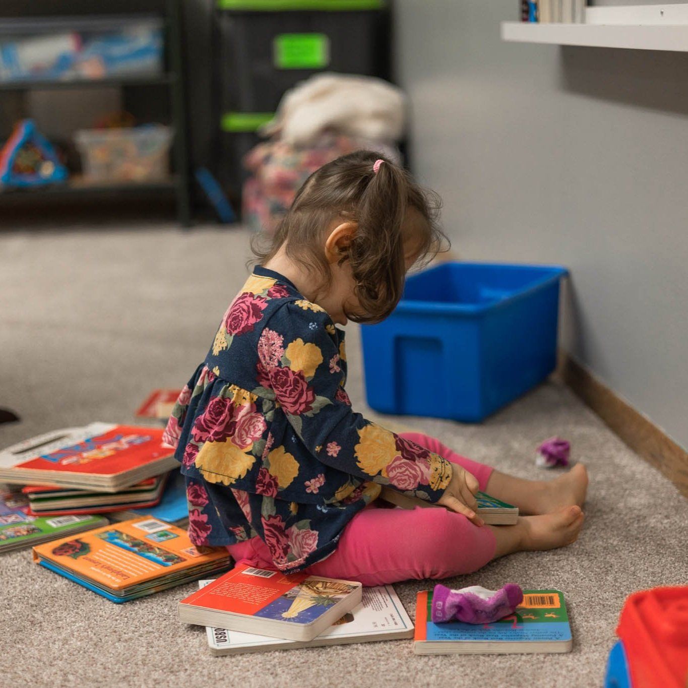 A little girl is sitting on the floor reading a book