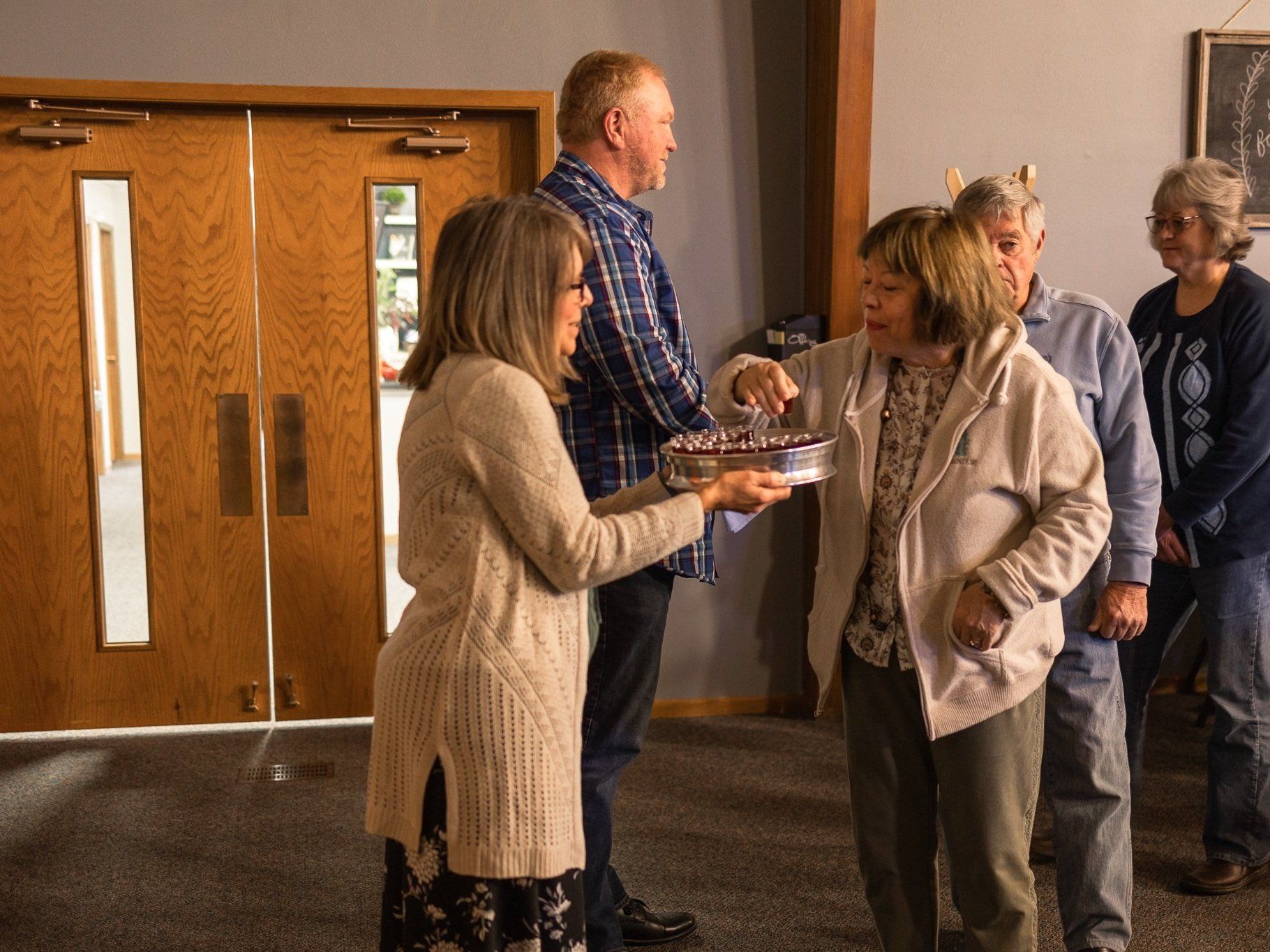 A group of people are standing around a woman holding a cake.