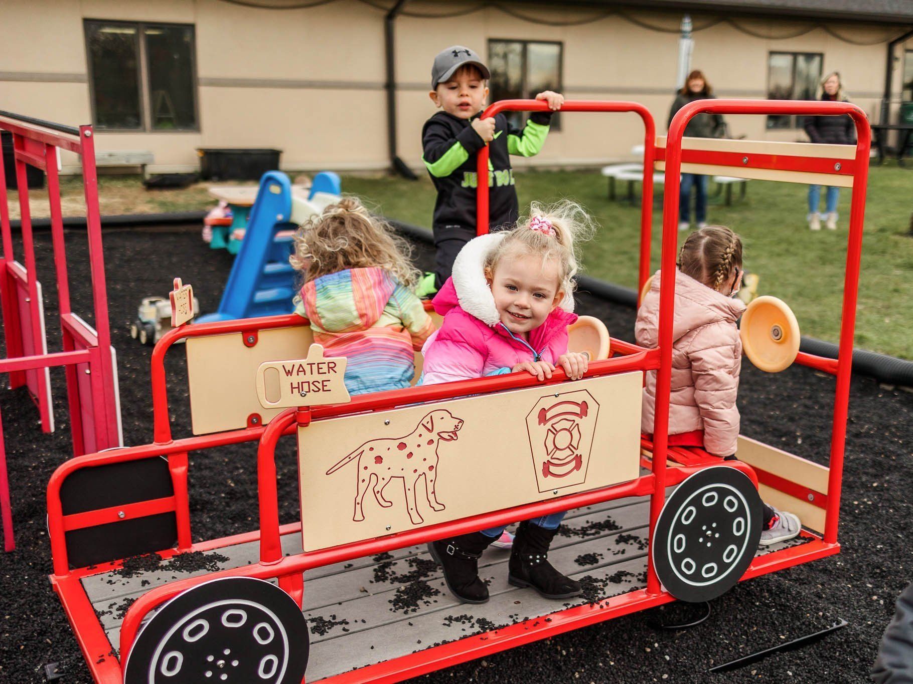 A group of children are playing on a toy train in a playground.