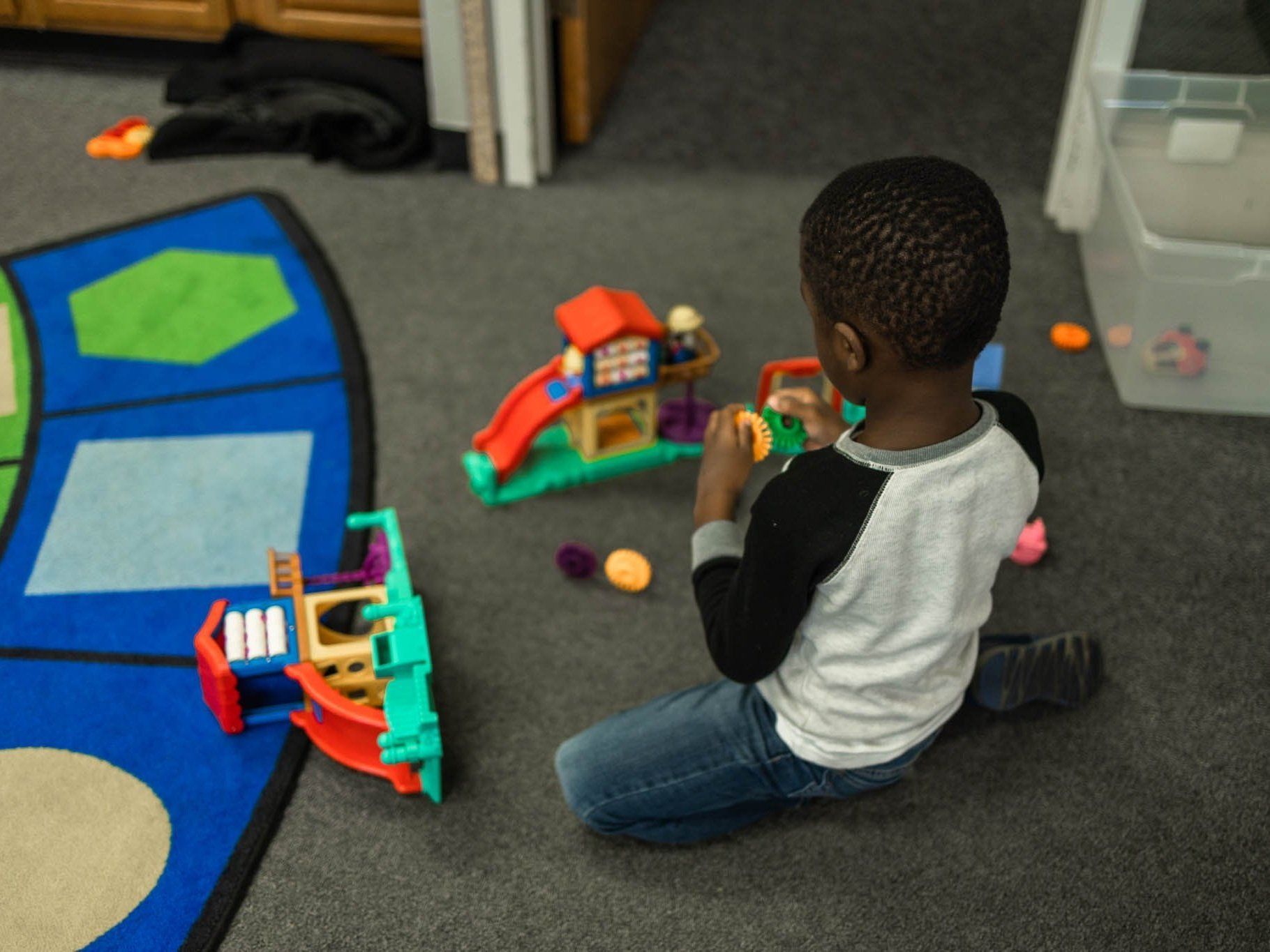 A young boy is playing with toys on the floor
