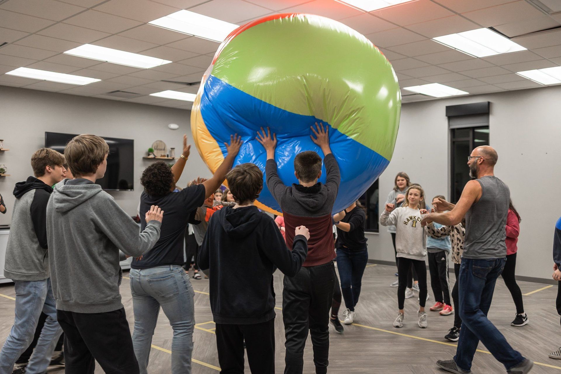 A group of people are playing with an inflatable beach ball in a room.