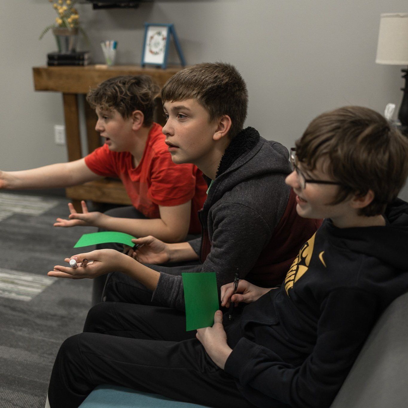 A group of young boys are sitting on a couch playing a game