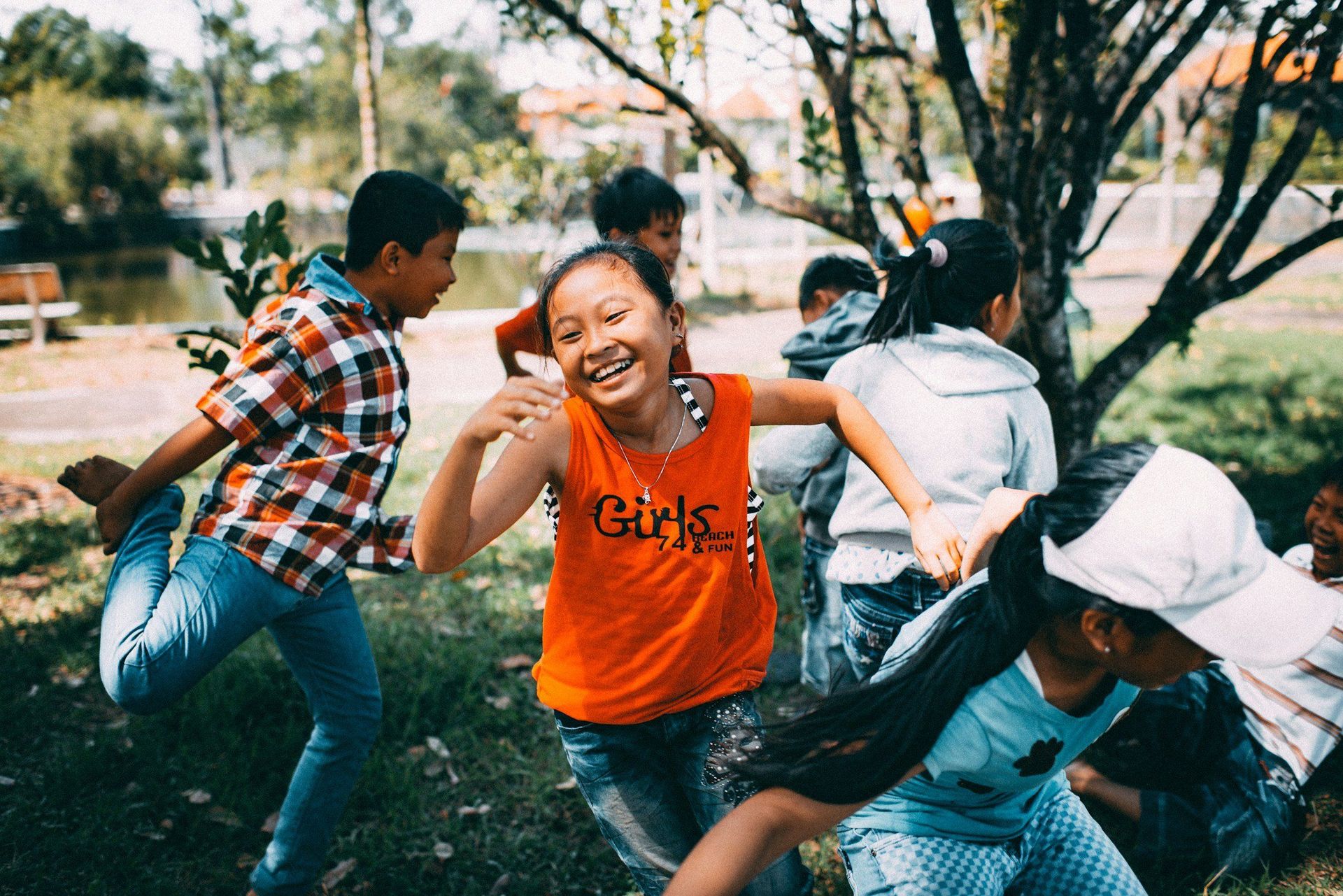 A group of children are playing in the grass under a tree.