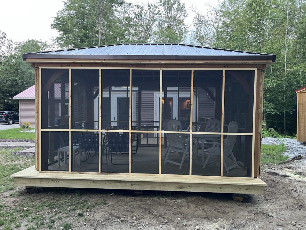 Screened-in gazebo with a dark roof and wooden frame, set on a wooden deck.