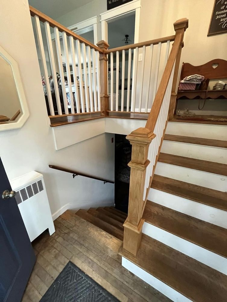 Staircase with wooden steps and white railing leading down to a lower level; doorway visible below.