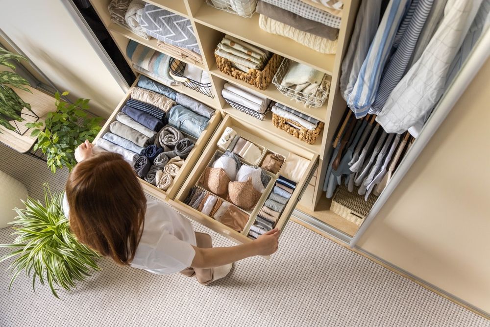 A woman is taking clothes out of a drawer in a closet.