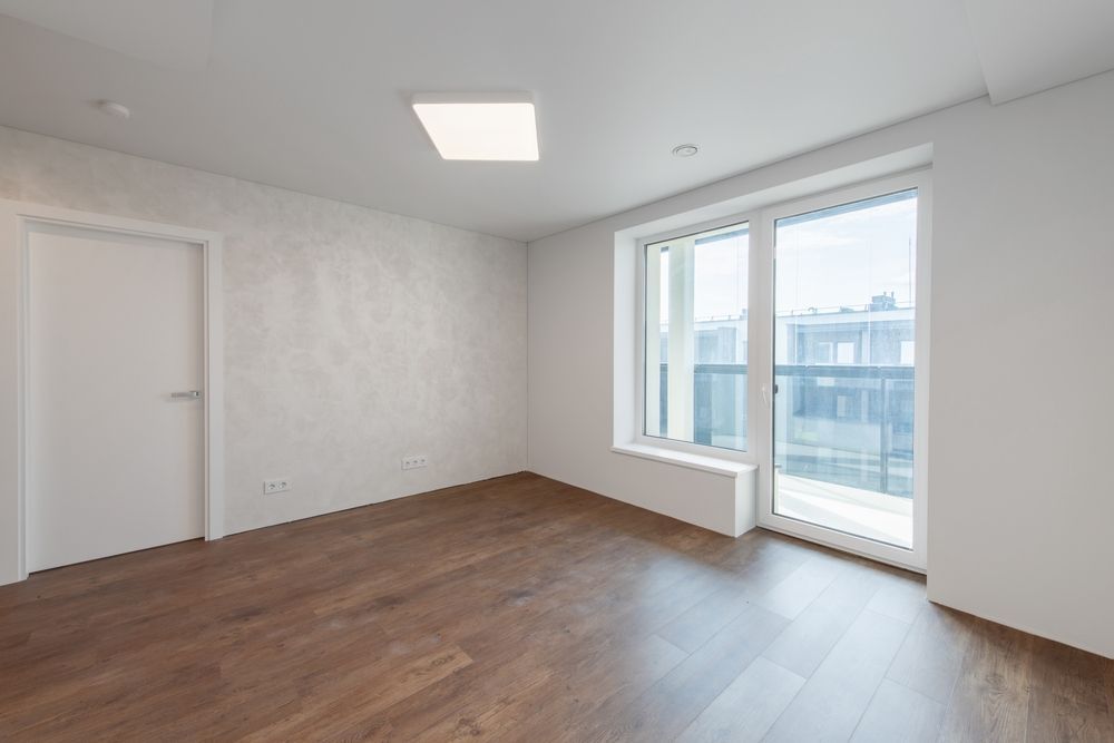 An empty room with hardwood floors and a balcony.