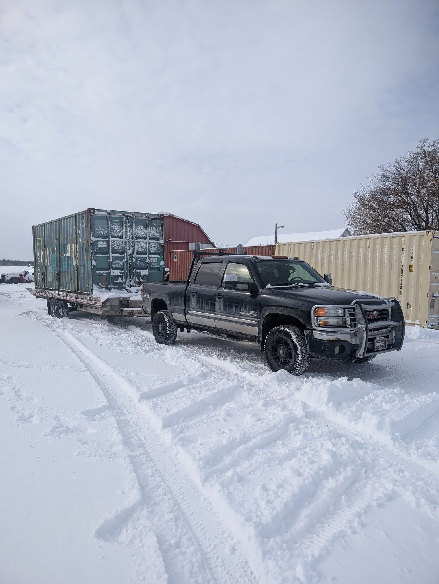 Un camion remorque un conteneur sur une remorque dans la neige.